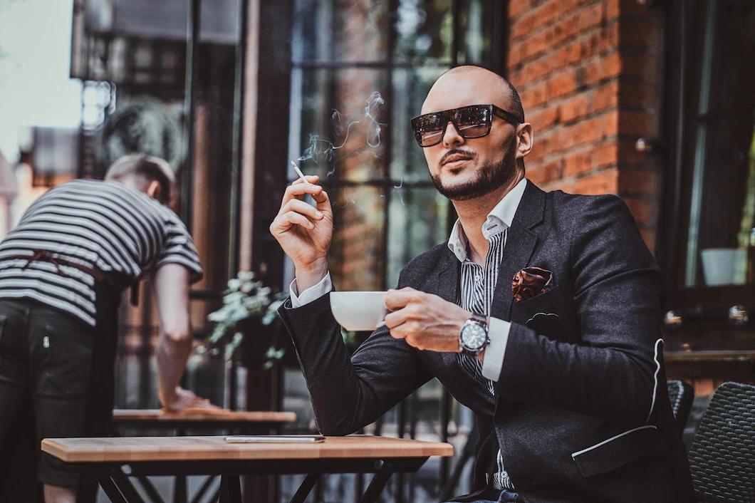 pensive modern man is smoking cigarette outside coffeshop while drinking his cup coffee 613910 20848