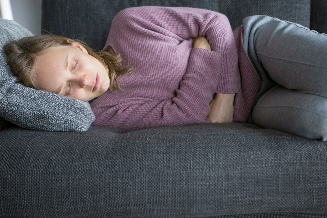 sick woman lying grey sofa home having legs bent 1262 18645