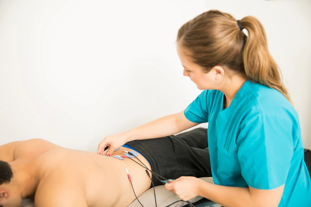 female physical therapist positioning electrodes customer lower back muscle treatment clinic 662251 1625